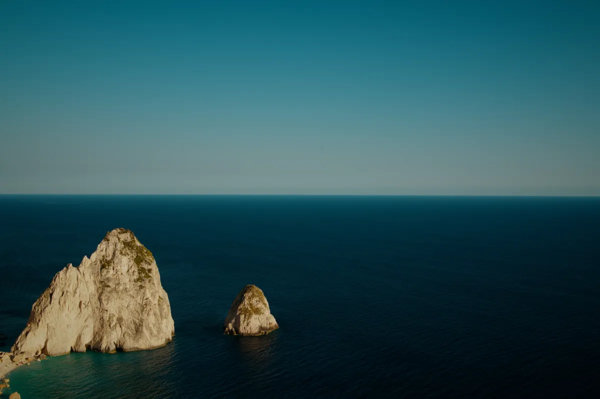 Two limestone sea stacks rising out of deep blue water.