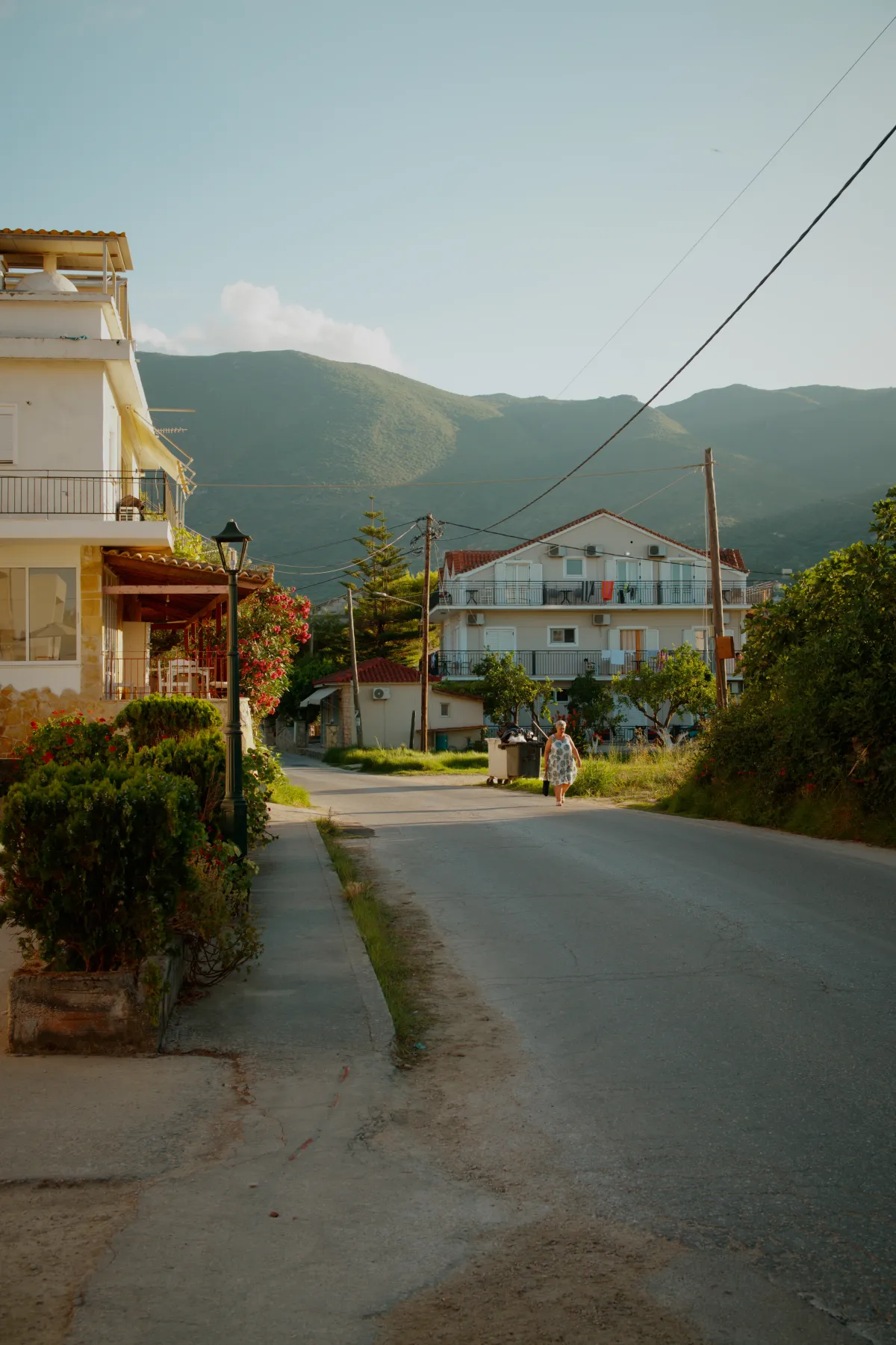 A quiet residential street with houses either side and mountains beyond.