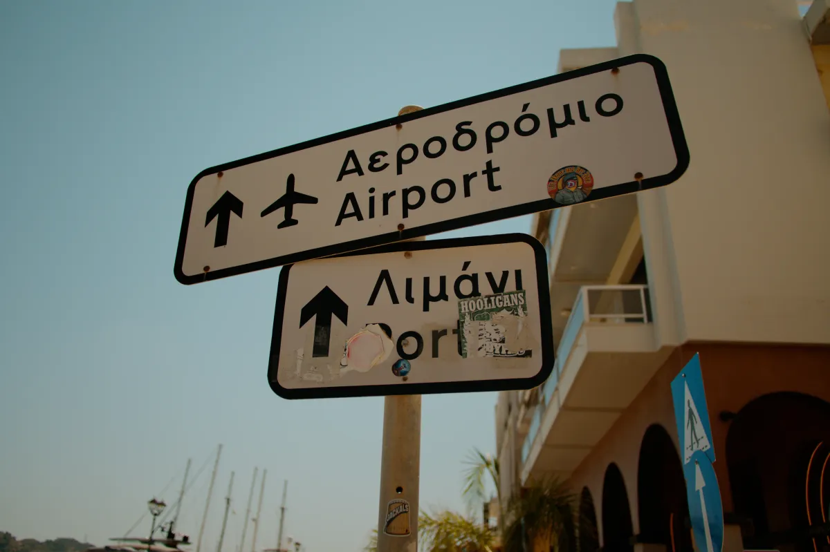 Road signs in Greek and English pointing to the airport and the port.