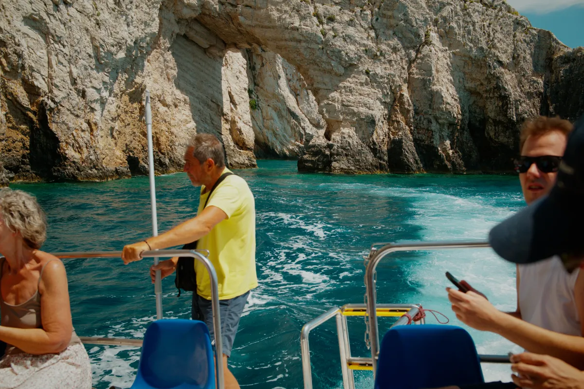 Passengers on a boat passing close beneath white limestone cliffs.