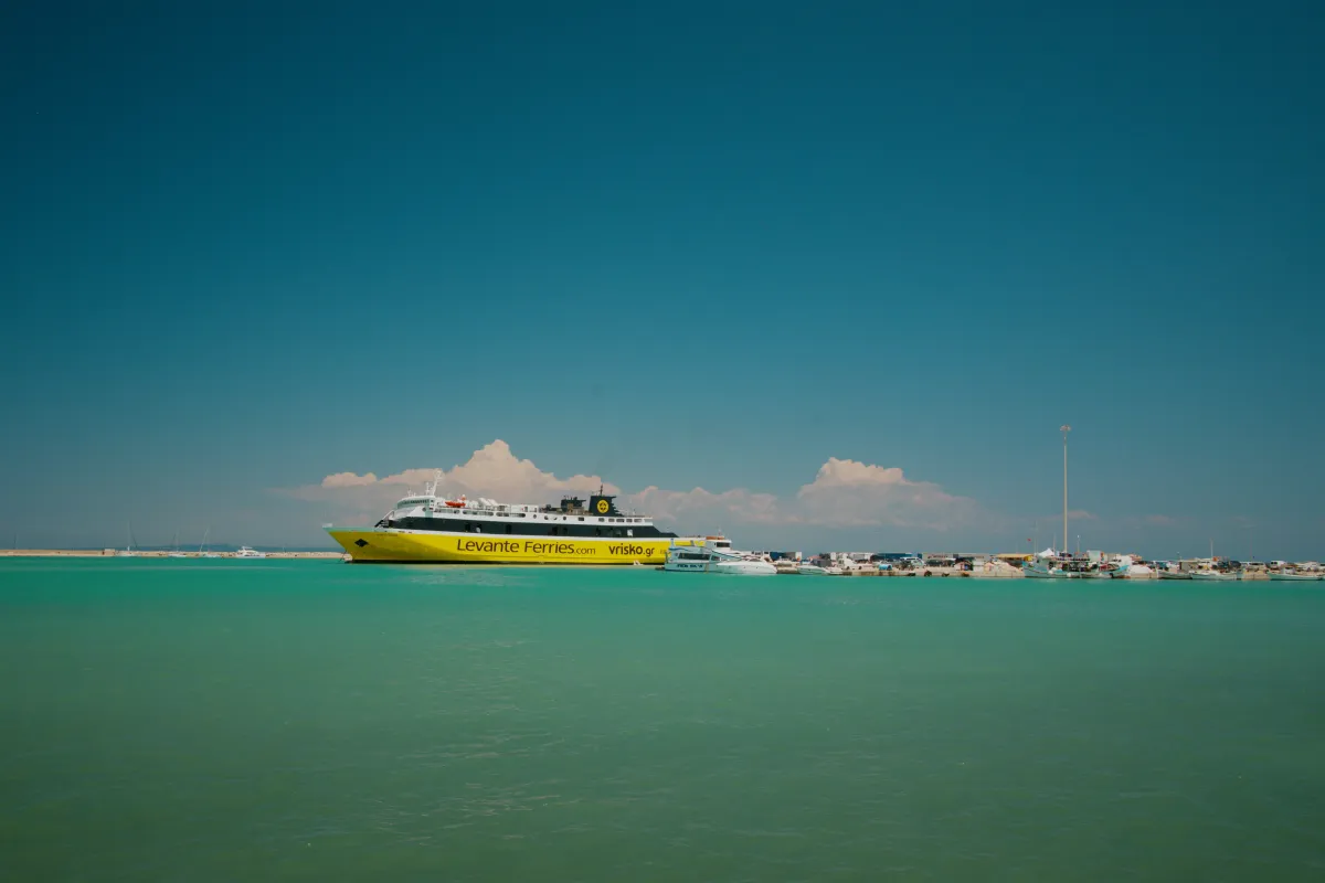 A yellow Levante Ferries catamaran on the water off a low shoreline.