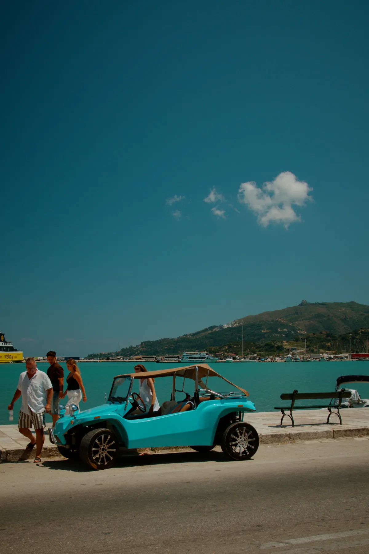 A turquoise beach buggy parked on the harbour front.