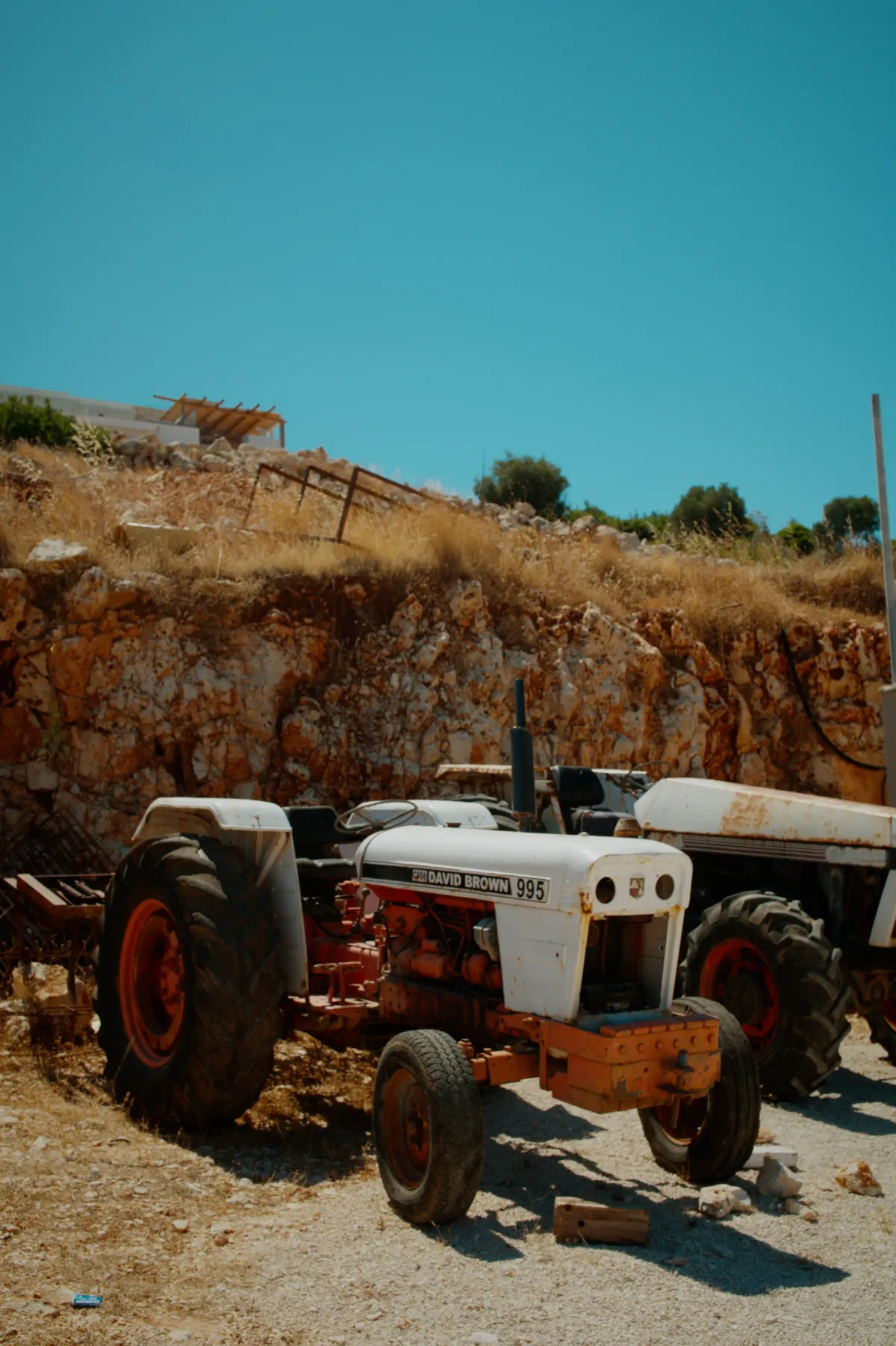 An old David Brown tractor parked in front of a rough stone wall.