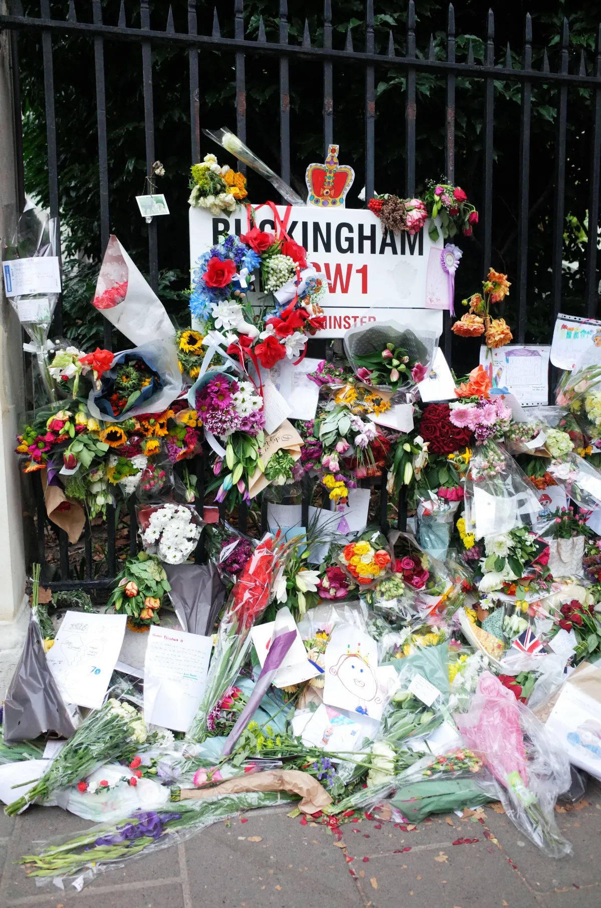 Flowers laid against a road sign which reads Buckingham SW1.