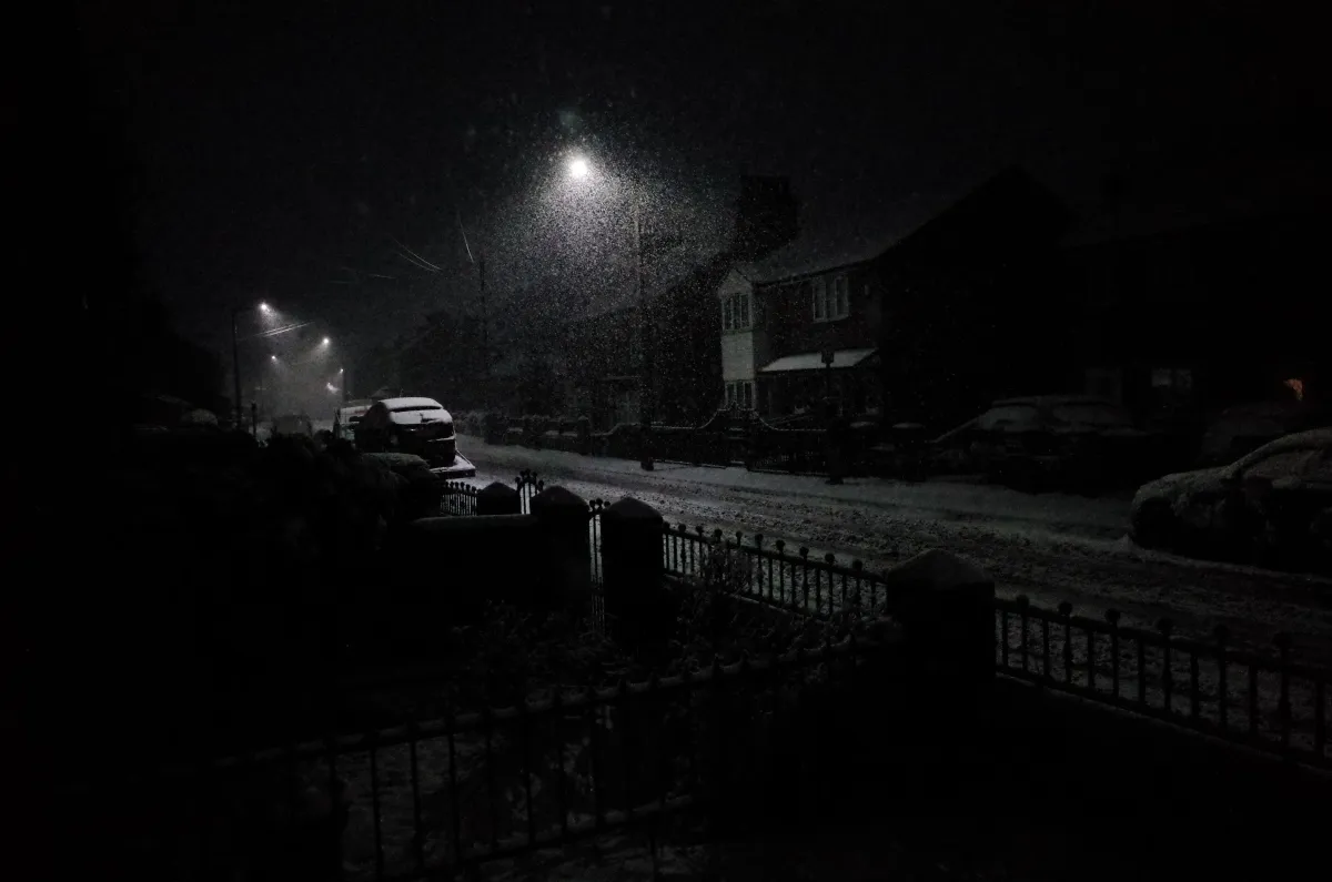 A dark street with only a streetlight for illumination.